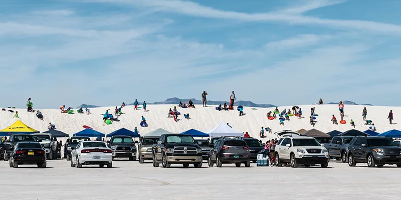 Visitors with saucer sleds and picnic shelters among the White Sands dunes