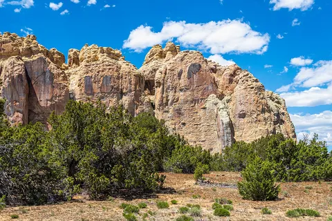 Sandstone cliffs rising above juniper trees at El Morro