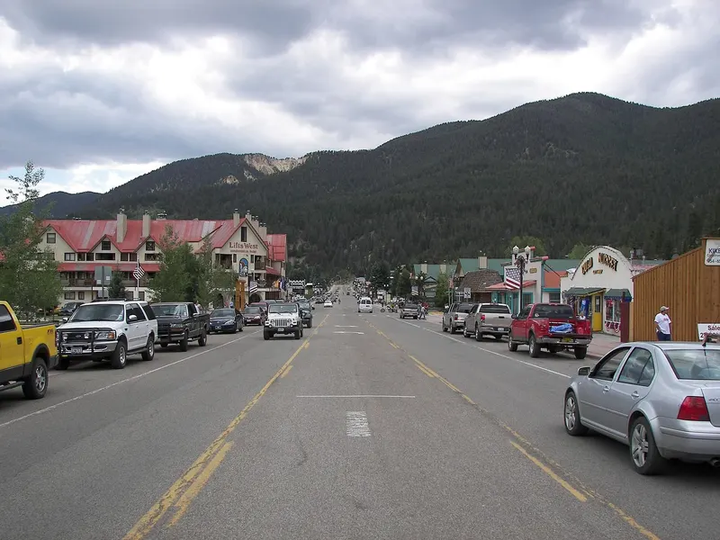 A summer street scene in Red River with forested mountains behind the town