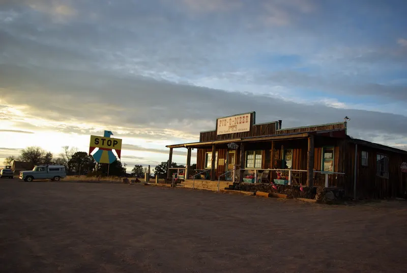 The wooden Pie-O-Neer cafe building beside the road in Pie Town at sunset
