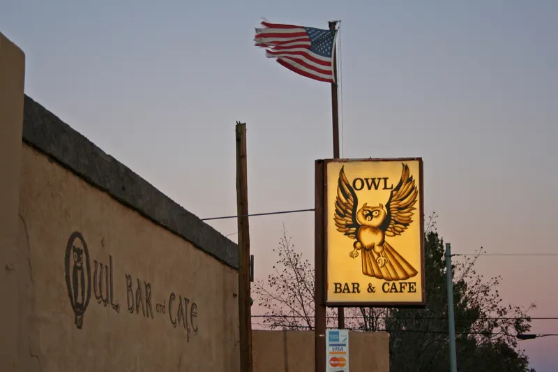 The Owl Bar and Cafe frontage and owl sign in San Antonio, New Mexico, at dusk